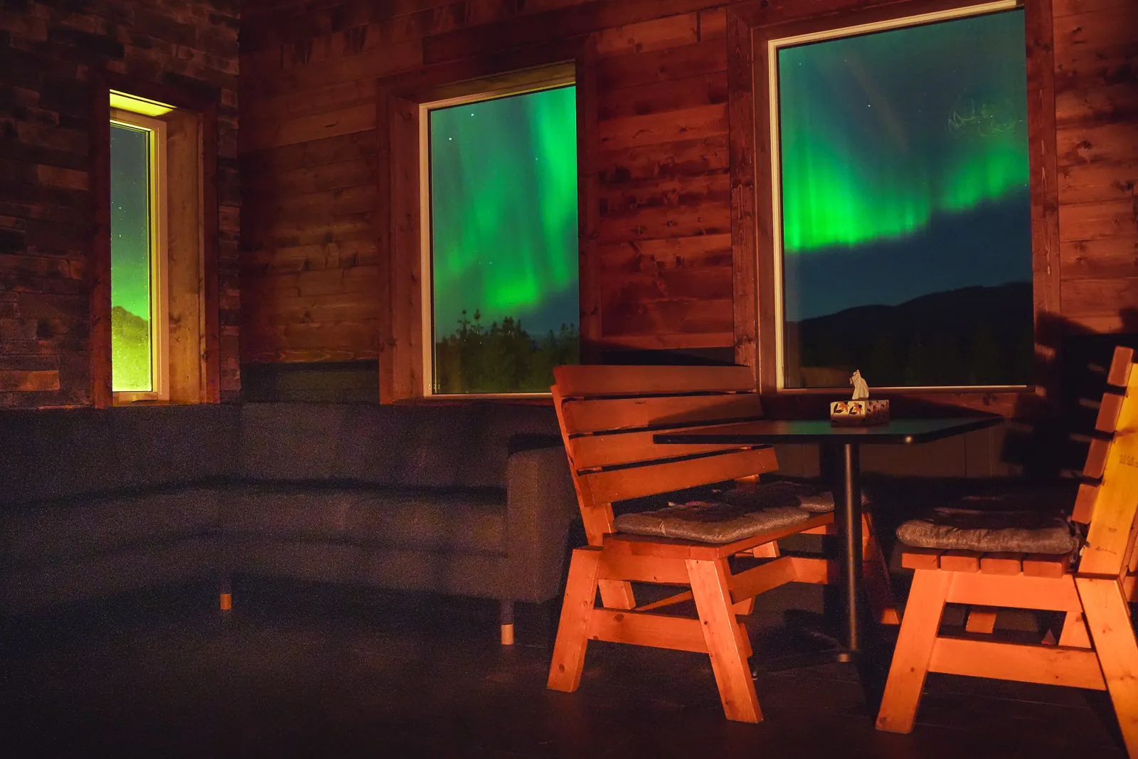Bright green northern lights filling the north-facing windows of the fire lit Aurora Lounge.